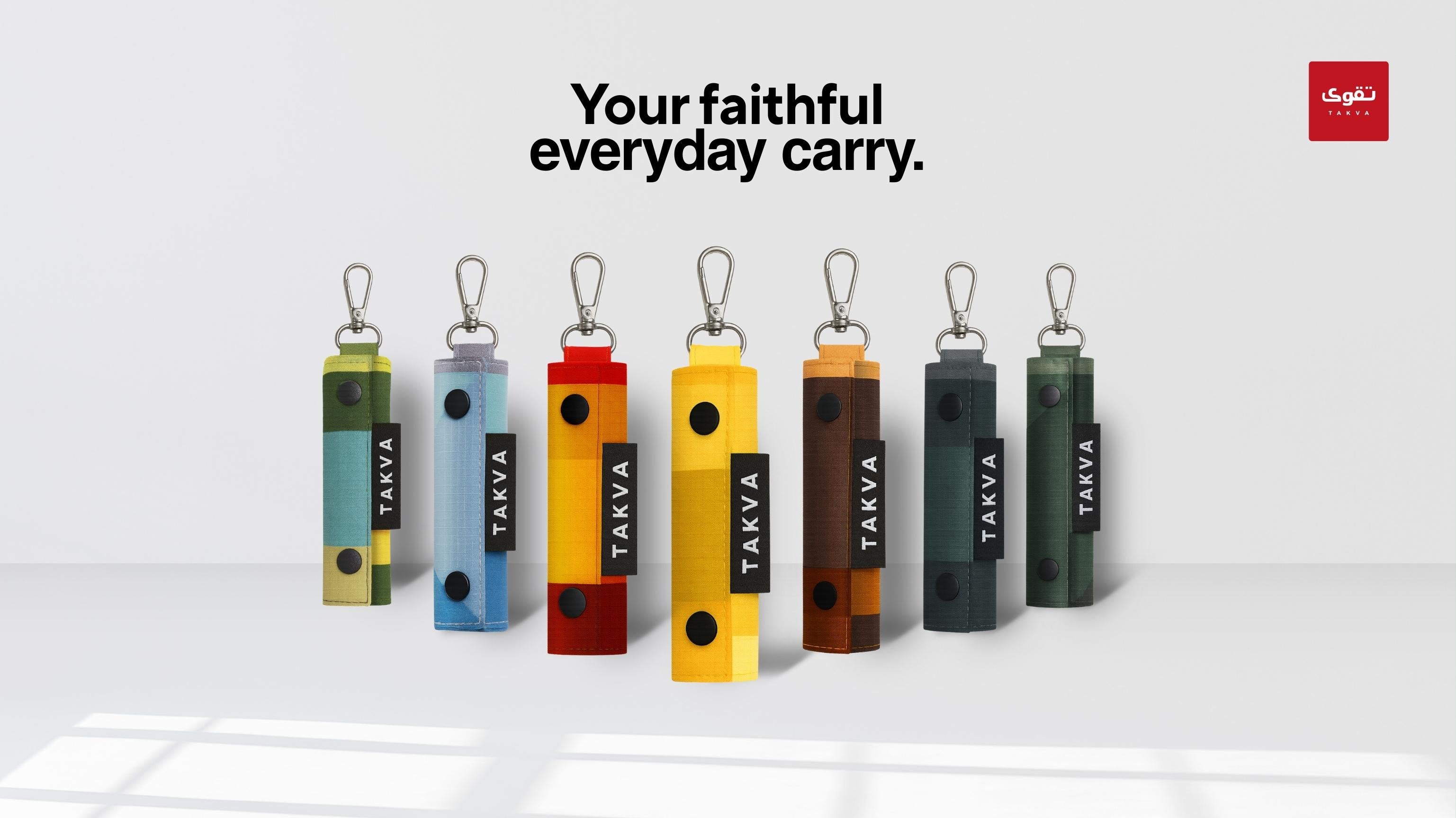 Seven SalahTag portable prayer mats in different colors with carabiner clips displayed in a row