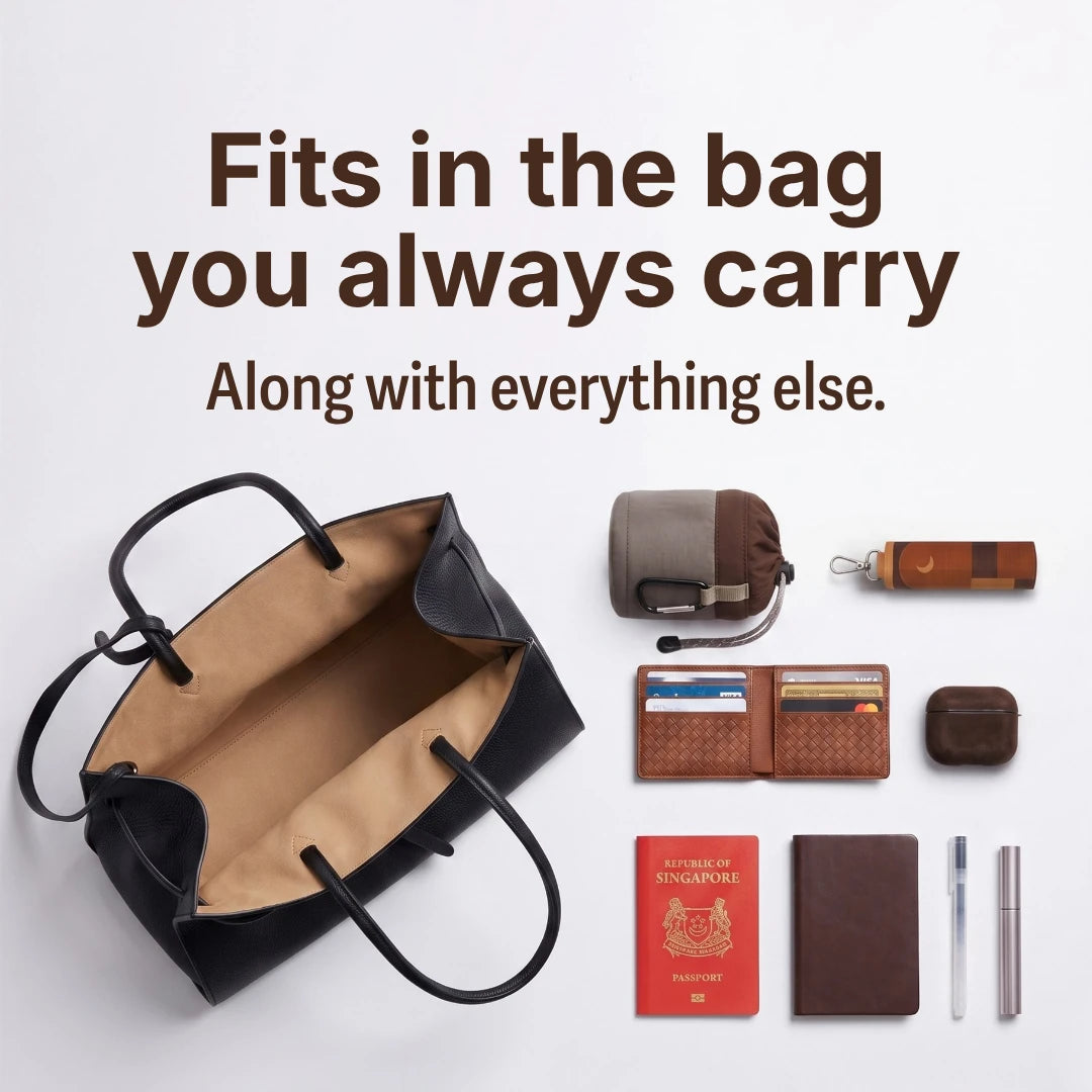 TAKVA SalahWear travel prayer dress pouch sitting inside an open black tote bag alongside a passport, wallet, wireless earbuds case, and pens — a compact prayer dress pouch that fits any everyday bag. (Mobile copy)